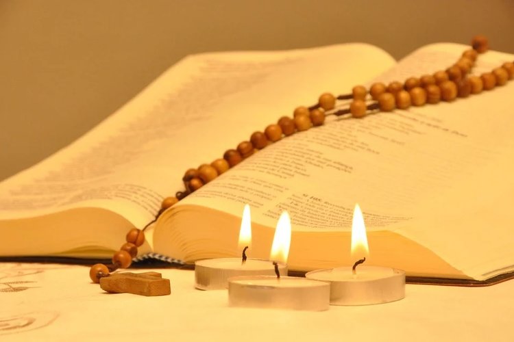 Raamattu, rukousnauha ja kynttilät.